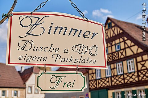 Ein Schild mit der Aufschrift "Zimmer" lädt zum Übernachten ein